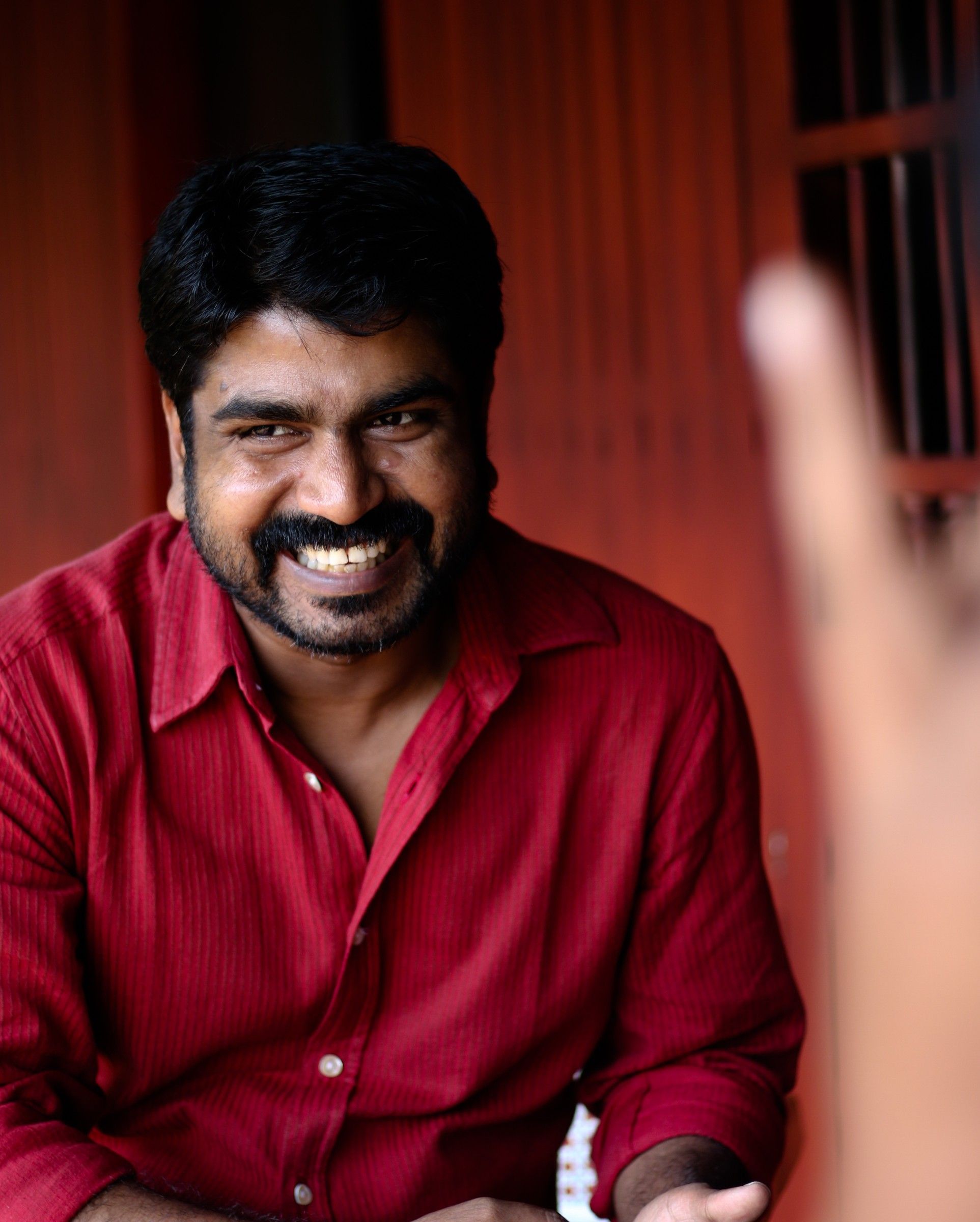 Sanju Surendran smiling in a red shirt, portrait