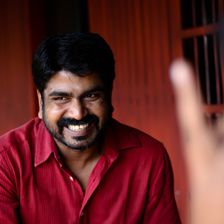 Sanju Surendran smiling in a red shirt, portrait
