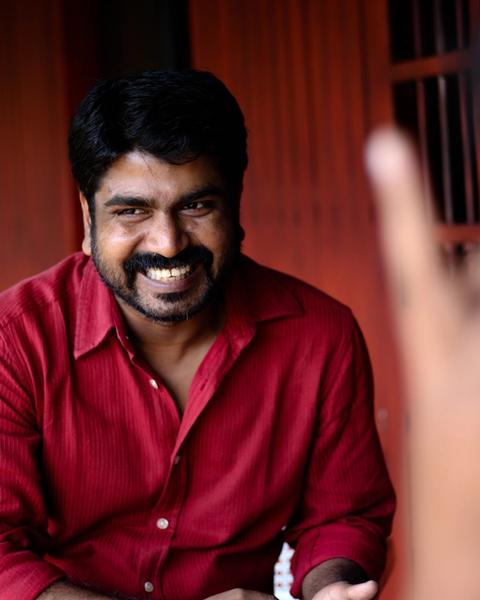 Sanju Surendran smiling in a red shirt, portrait