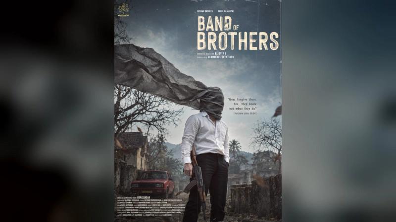 Band of Brothers first-look poster: hooded man in white shirt holding a rifle in a ruined village