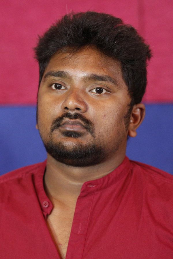 Bala Saravanan in a red shirt against a red and blue backdrop, head-and-shoulders portrait