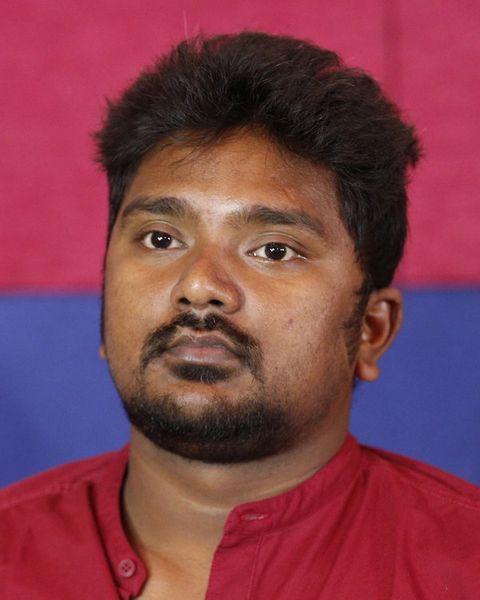 Bala Saravanan in a red shirt against a red and blue backdrop, head-and-shoulders portrait