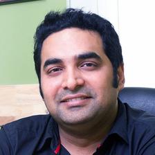 Gopi Sundar smiling in a dark shirt, seated indoors portrait