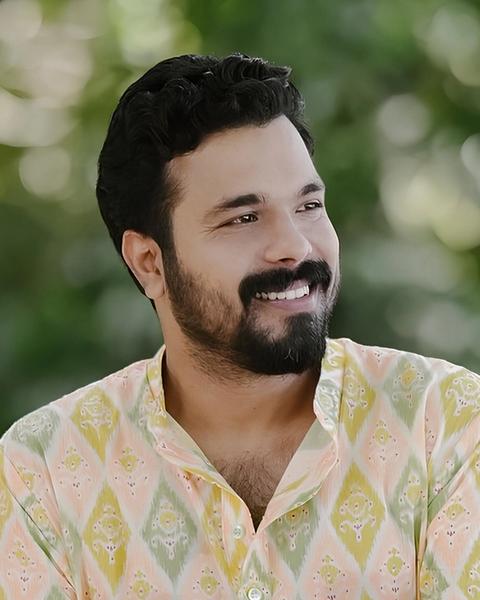 Abhiram Radhakrishnan smiling in a pastel ikat-print kurta, head-and-shoulders portrait