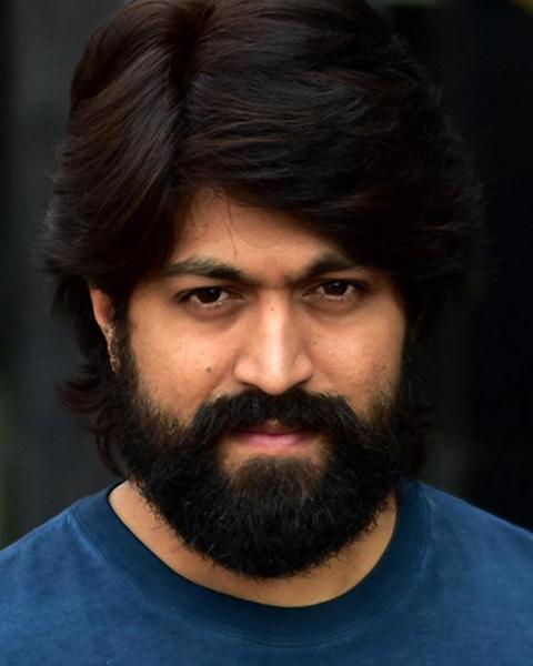 Yash with long hair and a full beard in a blue shirt, close-up portrait