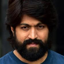 Yash with long hair and a full beard in a blue shirt, close-up portrait