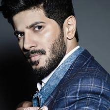Dulquer Salmaan in a checked blazer against a dark background, portrait