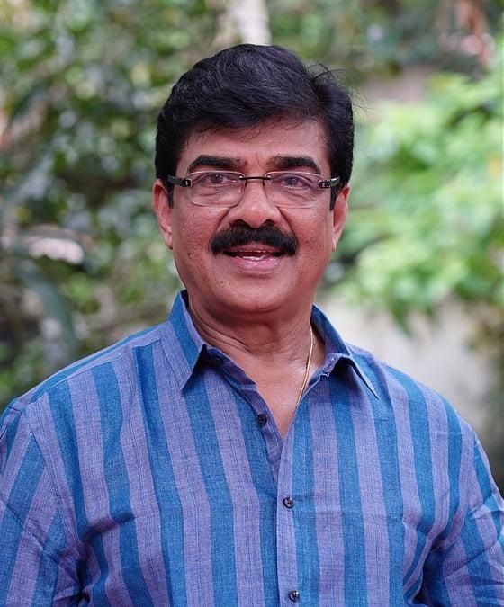 Vijayaraghavan in glasses and a blue striped shirt outdoors