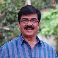 Vijayaraghavan in glasses and a blue striped shirt outdoors