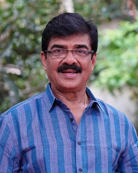 Vijayaraghavan in glasses and a blue striped shirt outdoors