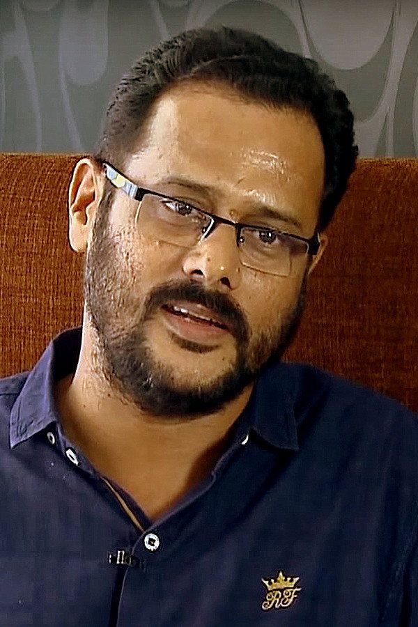 M. Padmakumar in glasses and a blue shirt