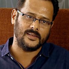 M. Padmakumar in glasses and a blue shirt