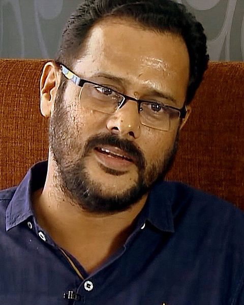 M. Padmakumar in glasses and a blue shirt