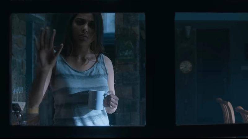 Spring trailer still: lead actress at a window holding a mug