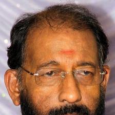 Nedumudi Venu with glasses and a grey beard, close-up portrait