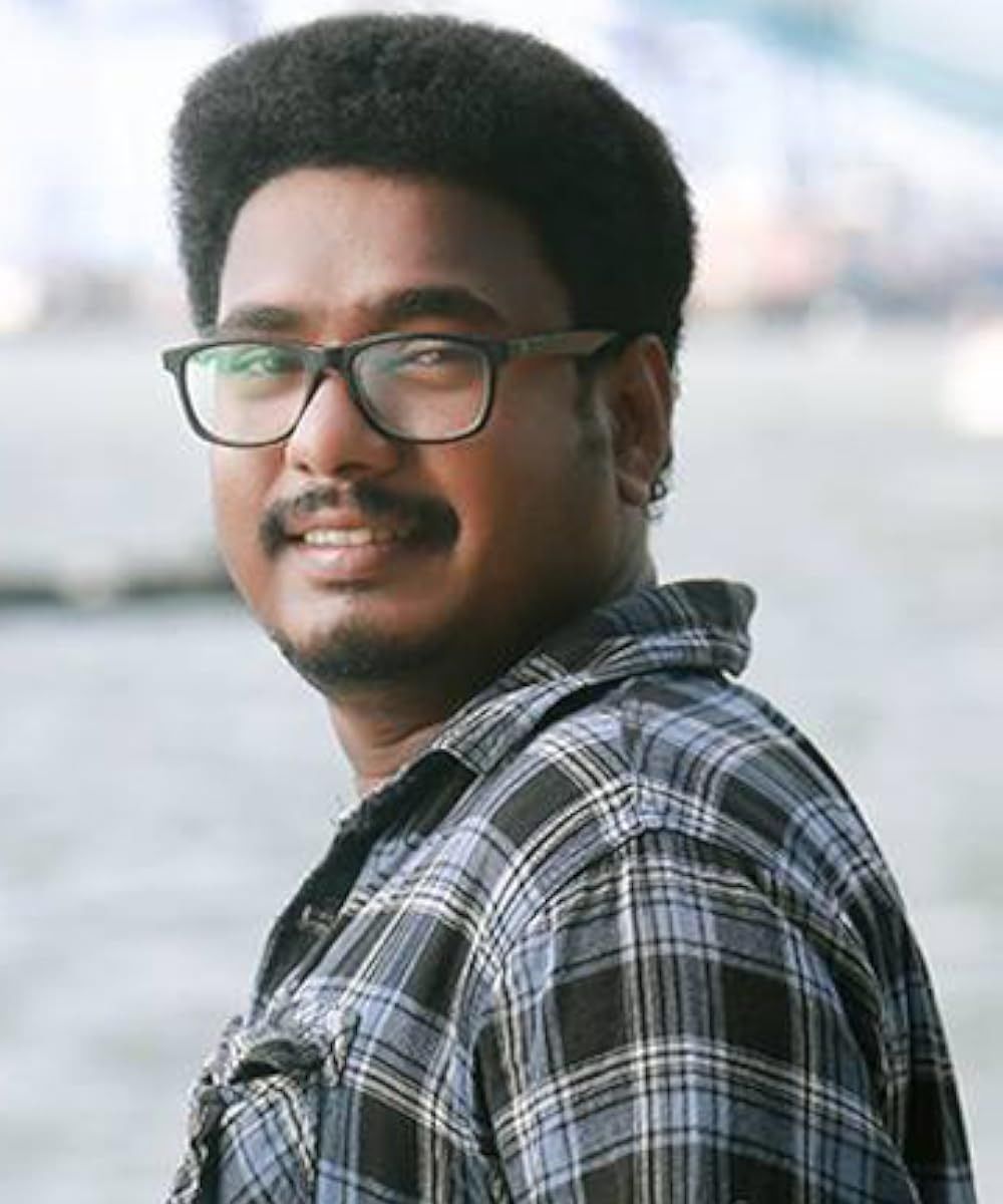 Aneesh Gopal in glasses and a checked shirt by a waterfront