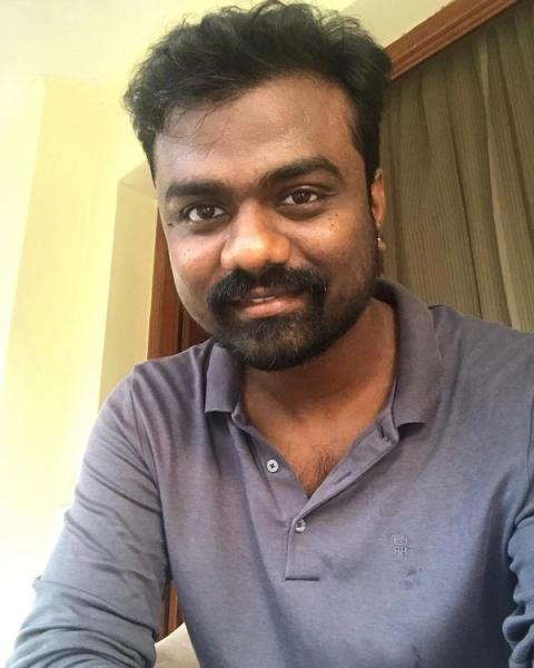 Director Rajkumar Periasamy smiling in a grey polo shirt, indoor selfie