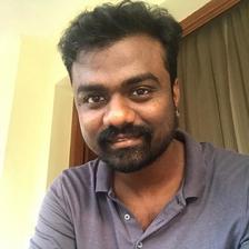 Director Rajkumar Periasamy smiling in a grey polo shirt, indoor selfie