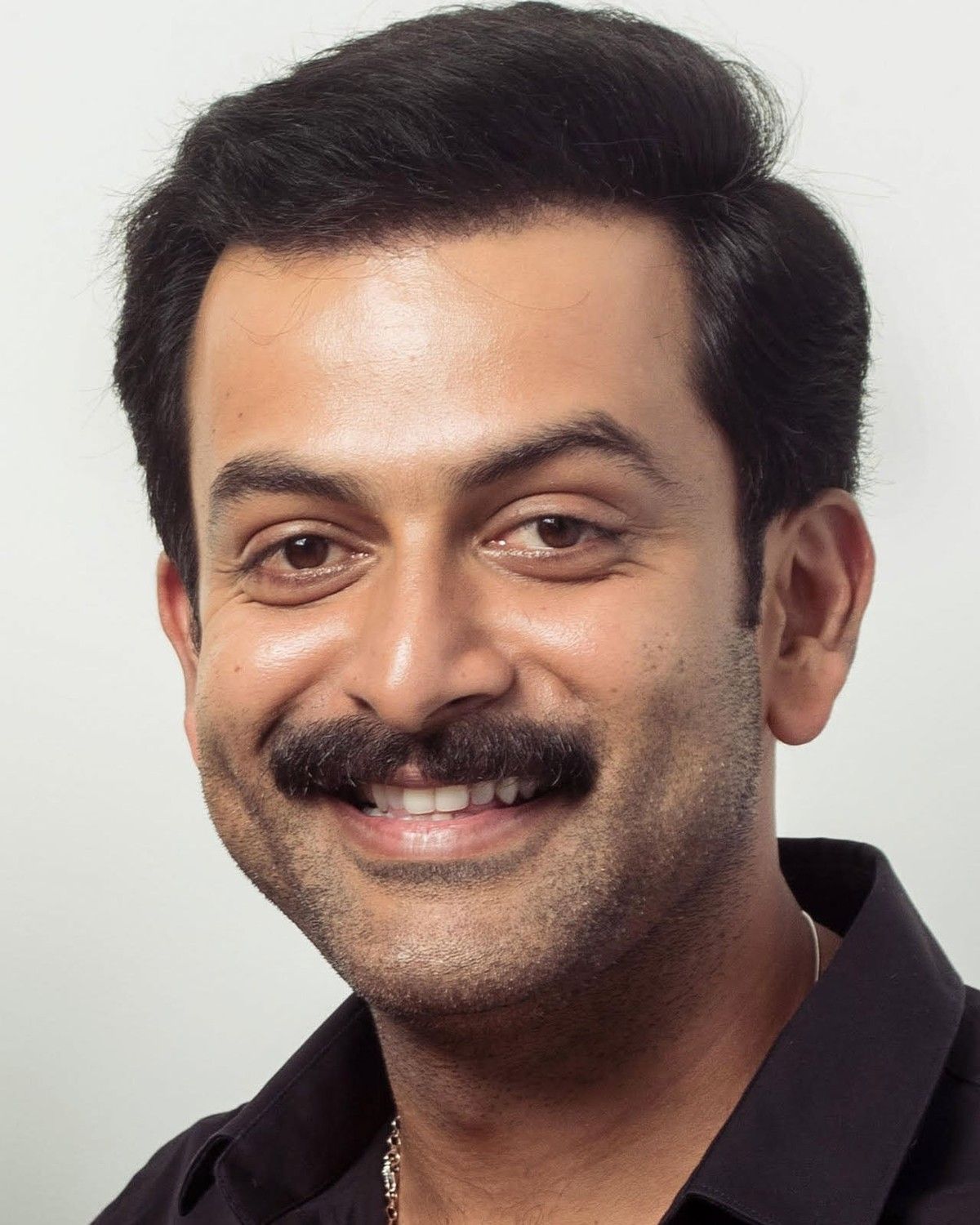Prithviraj Sukumaran smiling with a moustache, close-up portrait