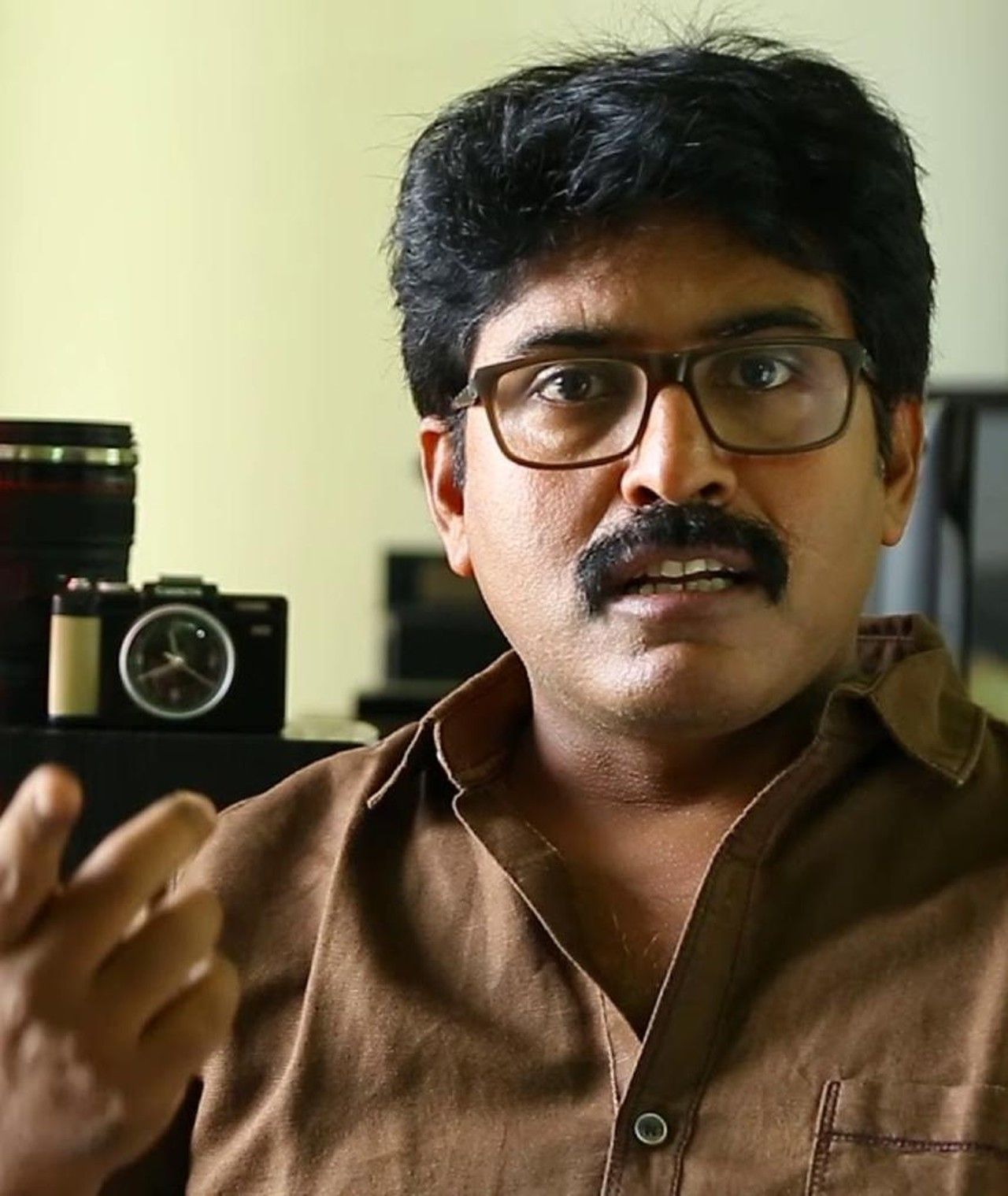 Shamdat Sainudeen in glasses and a brown shirt, portrait