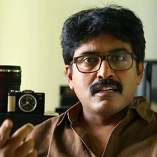 Shamdat Sainudeen in glasses and a brown shirt, portrait