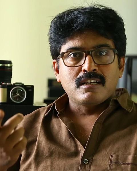 Shamdat Sainudeen in glasses and a brown shirt, portrait