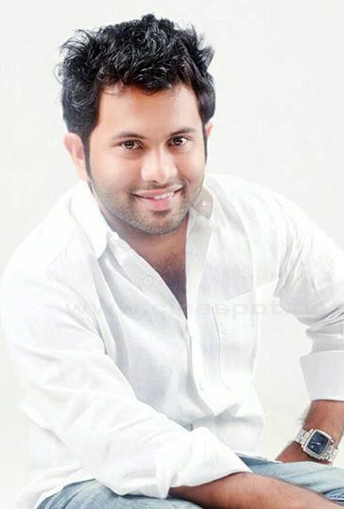 Aju Varghese smiling in a white shirt against a plain background