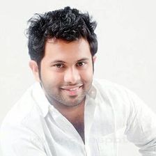 Aju Varghese smiling in a white shirt against a plain background