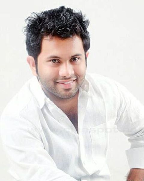 Aju Varghese smiling in a white shirt against a plain background