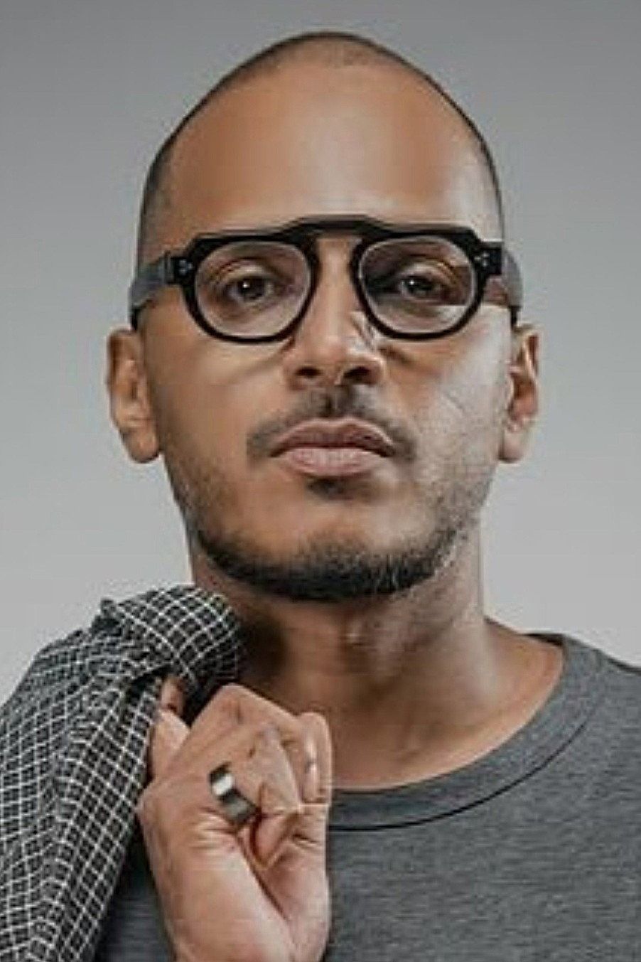 Mujeeb Majeed in black glasses holding his collar, portrait