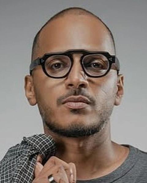 Mujeeb Majeed in black glasses holding his collar, portrait