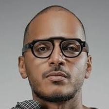Mujeeb Majeed in black glasses holding his collar, portrait
