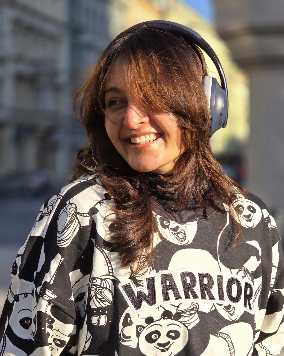 Manju Warrier smiling in headphones and a printed panda sweatshirt