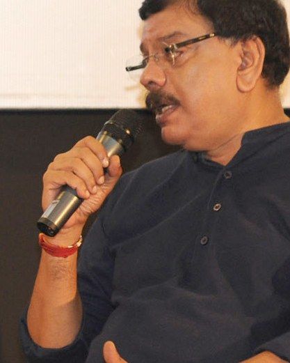 Priyadarshan speaking into a microphone in a dark shirt
