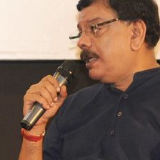 Priyadarshan speaking into a microphone in a dark shirt
