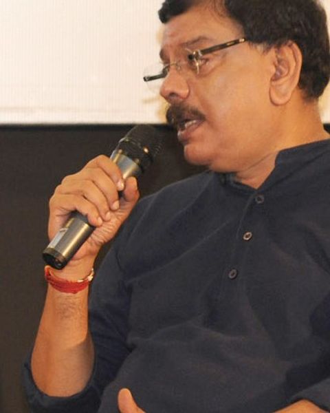 Priyadarshan speaking into a microphone in a dark shirt