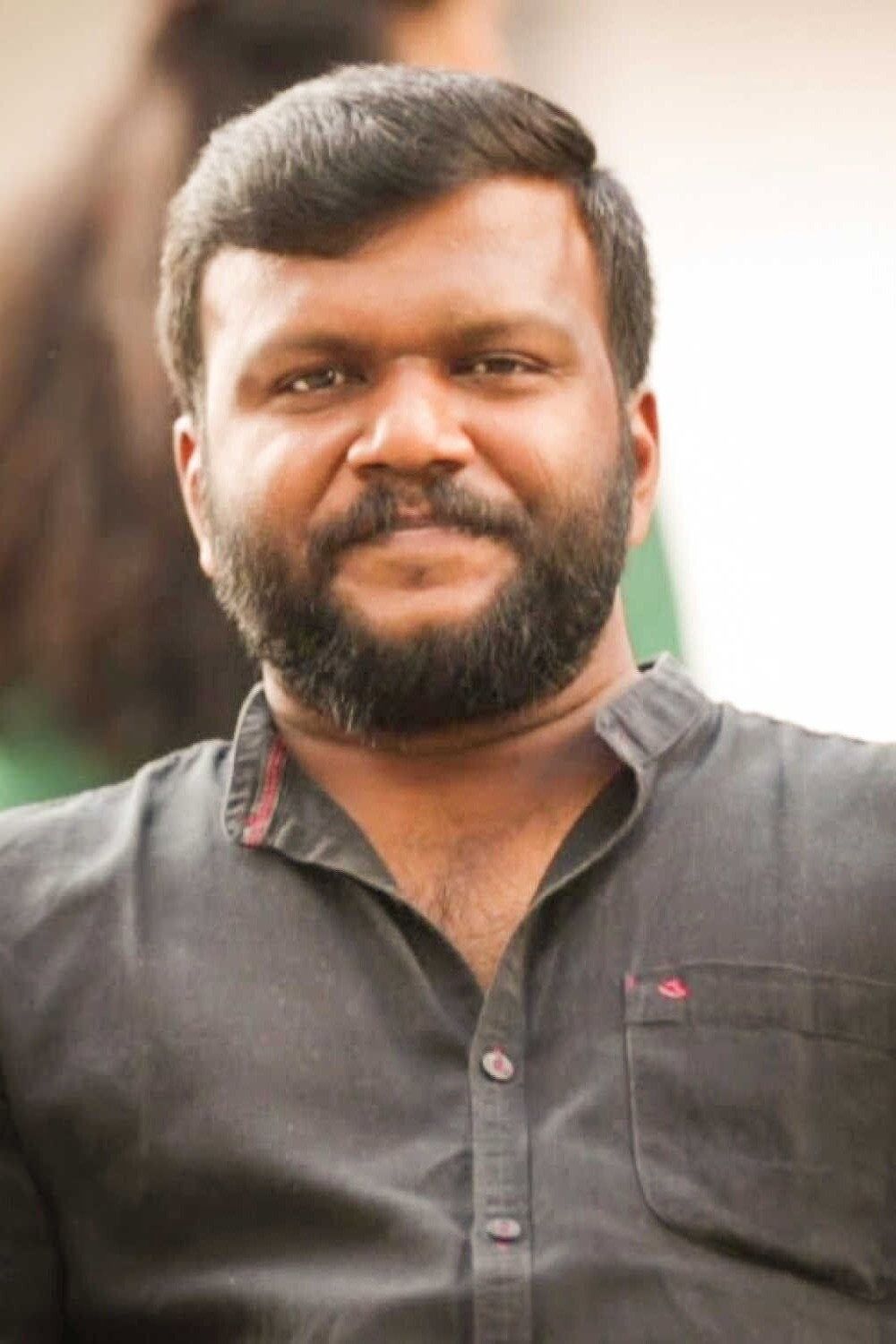 Manu Ashokan with a beard in a grey shirt, close-up portrait