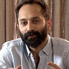 Fahadh Faasil with a beard in a grey shirt, gesturing while talking