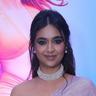 Keerthy Suresh smiling in a lilac sari and pearl choker at a film event