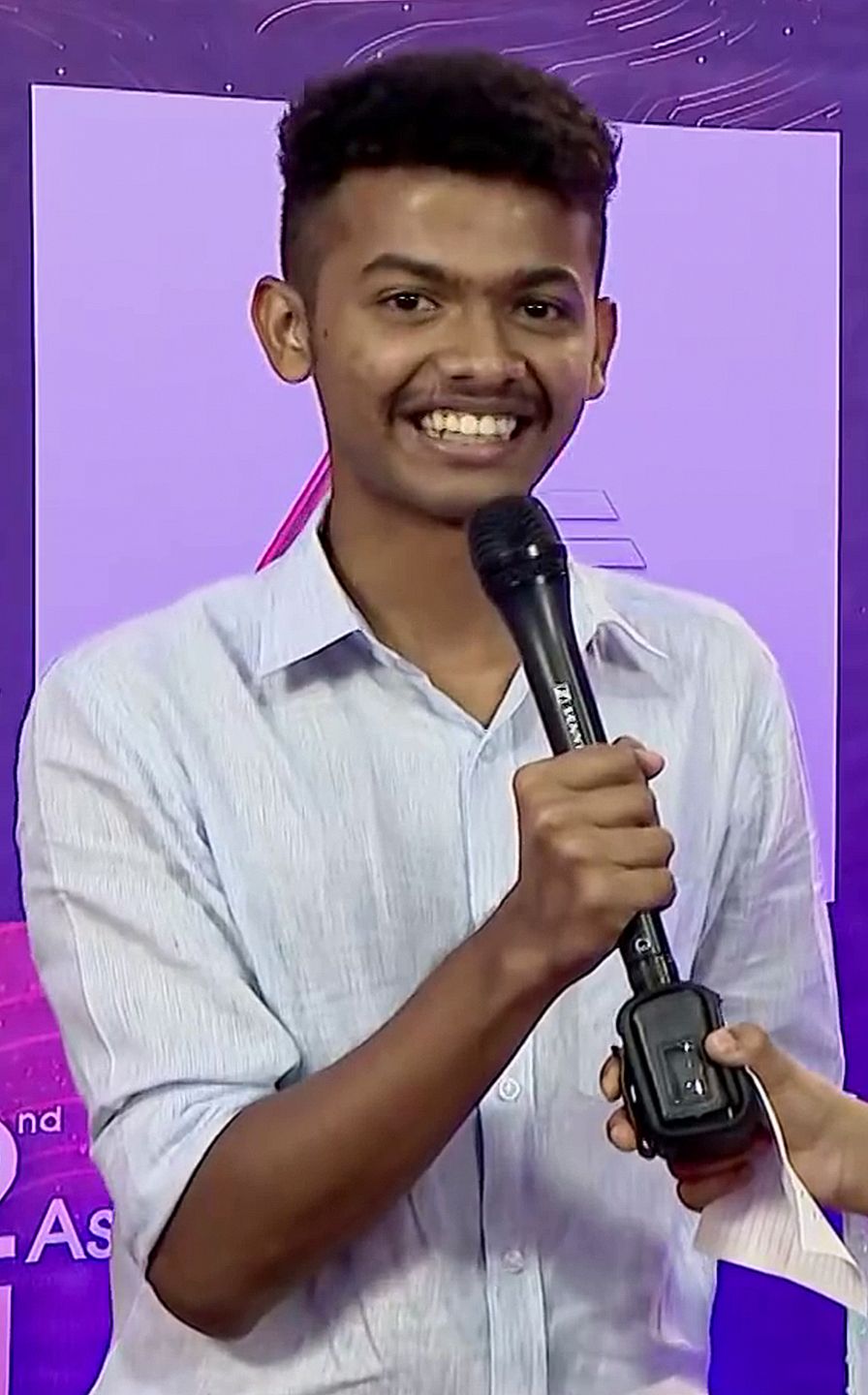 Mathew Thomas smiling and holding a microphone at an event