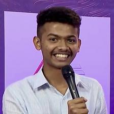 Mathew Thomas smiling and holding a microphone at an event
