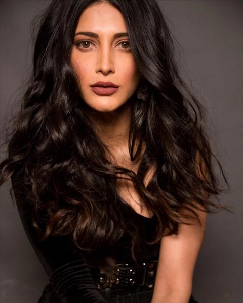 Shruti Haasan with long wavy hair in a black outfit, portrait
