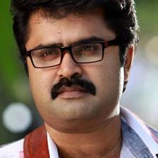 Anoop Menon in glasses with a moustache, close-up outdoor portrait