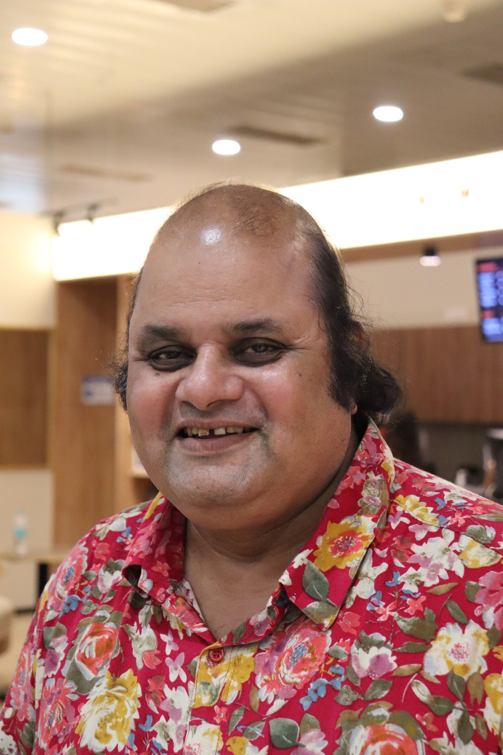 Sunil Sukhada smiling in a floral shirt, portrait