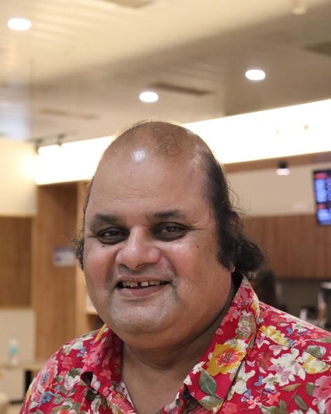 Sunil Sukhada smiling in a floral shirt, portrait