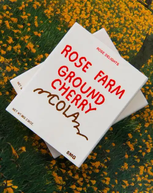 Ground cherry cola Rose Delights packaging lay flat in a bed of California poppies.