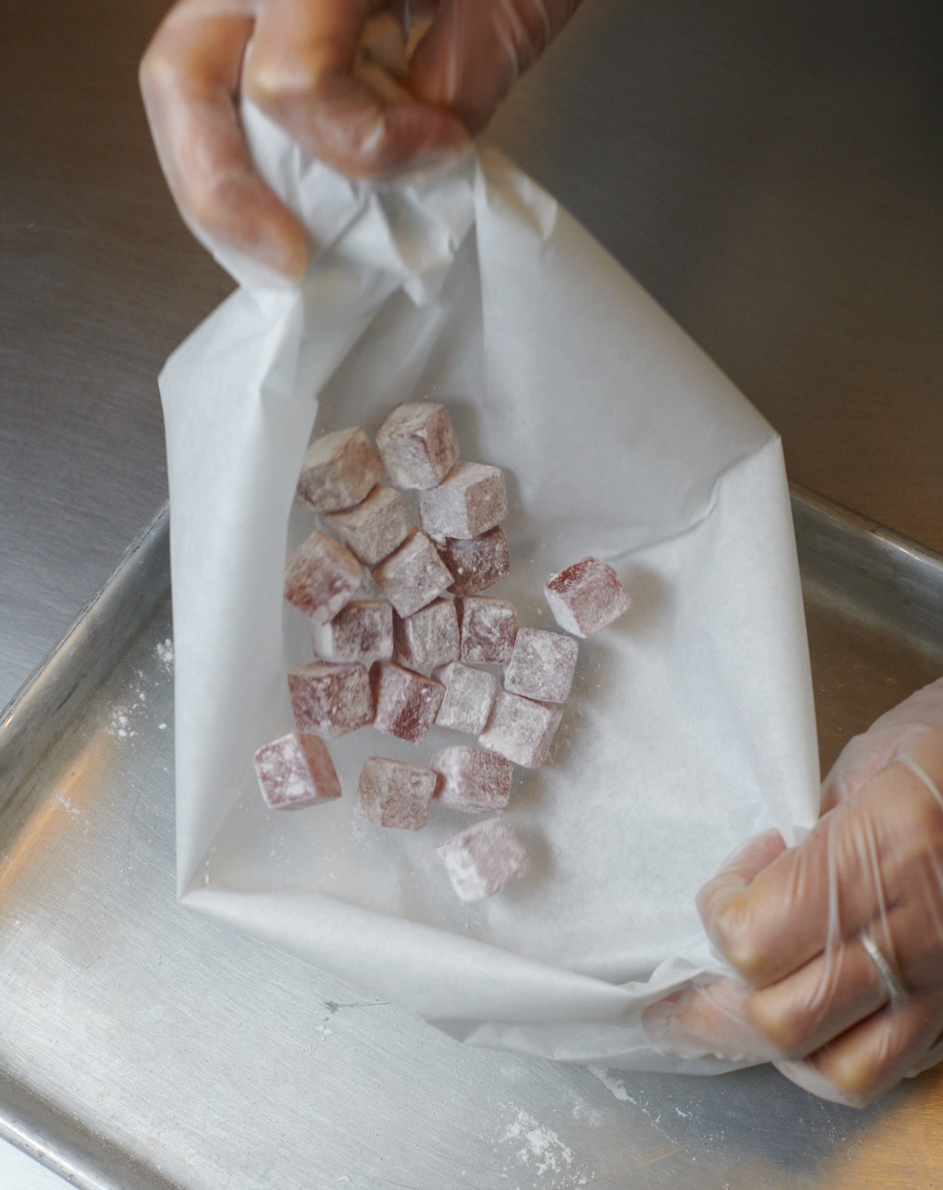 Delights being coated in powered sugar in the kitchen.