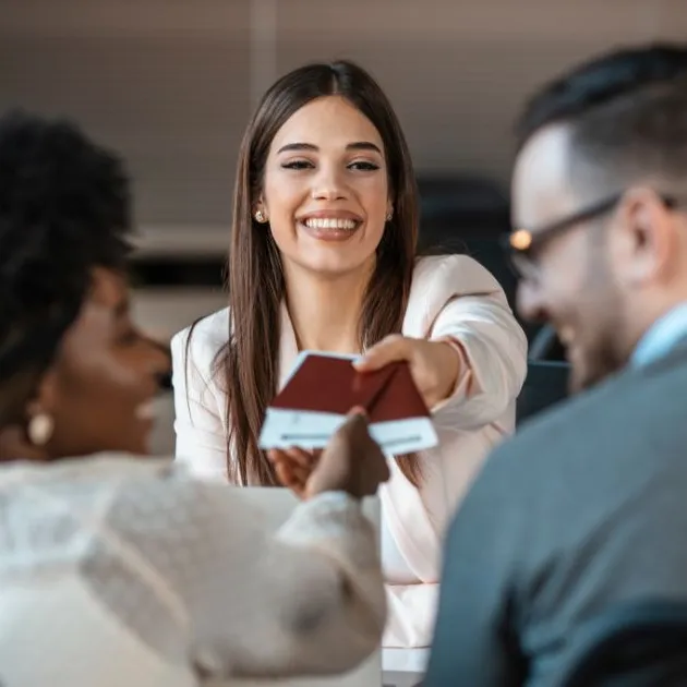 A cheerful professional handing passports to clients, symbolizing assistance with visa applications and international travel support.