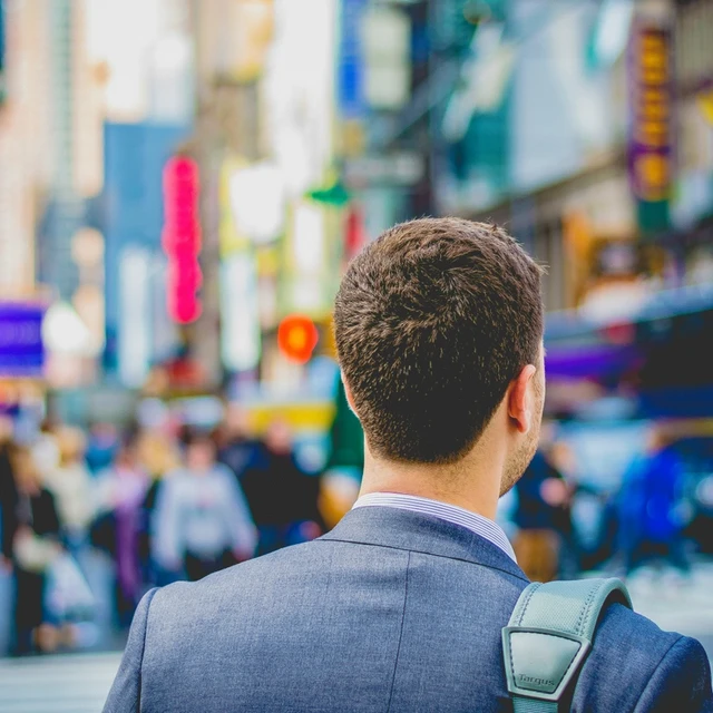 A student on a busy street looking at a building in the city