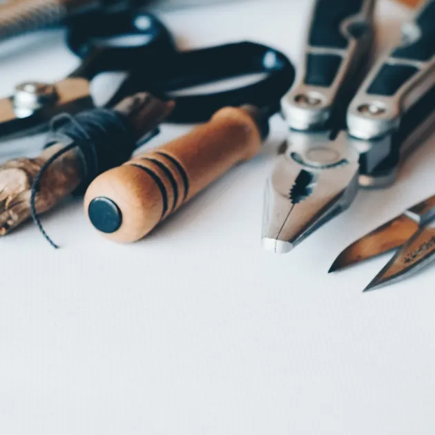 A set of crafting tools, including scissors, pliers, and wire, neatly arranged on a table, representing precision and creativity in craftsmanship.